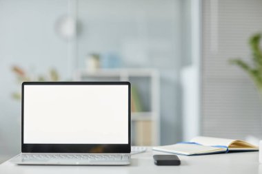 Ofis içi beyaz ve gri tonlarda beyaz ekran modeliyle açılan dizüstü bilgisayarın minimal arkaplan görüntüsü, boşluğu kopyala