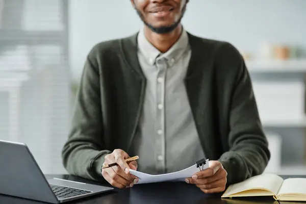 Close up of young black man holding CV with cover letters in job interview, copy space