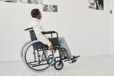 Modern sanat galerisini ziyaret ederken tekerlekli sandalye kullanan siyahi genç adam, kopyalama alanı