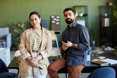 İki başarılı tasarımcı ya da beyaz yakalı işçiler iş yerinde kameraya bakıyor.
