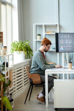 Genç, ciddi bir ofis çalışanı dizüstü bilgisayarın önünde oturmuş online bilgi ararken projeye hazırlanıyor.
