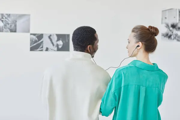 带耳机的年轻夫妇在博物馆一起观看抽象艺术的最低背景图 复制空间 — 图库照片