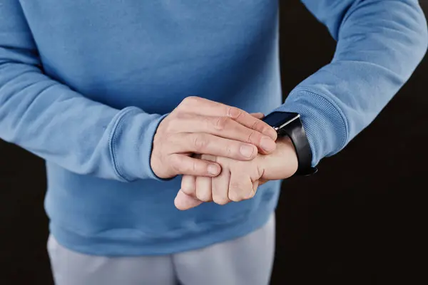Minimal closeup of man checking smartwatch against black background, copy space