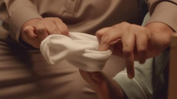 无法辨认的照顾奶奶把小白袜穿在孙子孙女的脚上 晚上让他睡在床上 — 图库视频影像