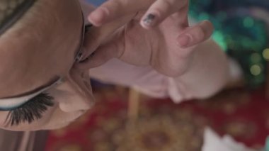 Yukarıdan, parlak göz makyajlı, kulis odasında gösteri için hazırlanırken sahte kirpiklerini takan beyaz, tuhaf bir adamın yakın planından.