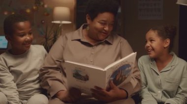 Orta sınıf Afro-Amerikan büyükannelerin çocuksu yatak odalarında yataklarında oturup onlara masal okuması.