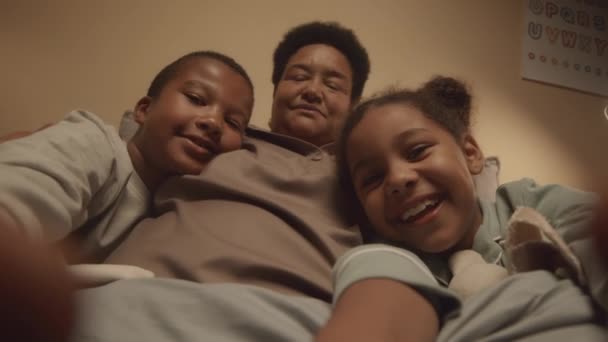 在孩子们录下他们自己的视频和他们快乐的祖母在床上玩得开心的时候 手持式Pov的快乐的非洲裔美国人 — 图库视频影像