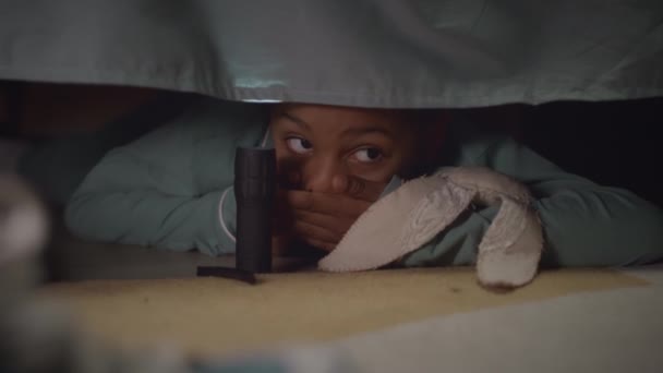 非洲裔美国女孩手握手电筒 躲在黑暗的房间里 躲在床下怪物的中间 — 图库视频影像