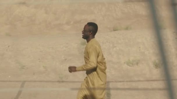 뜨거운 사막을 달리는 노란색 의복에서 즐거운 아프리카계 미국인 남자의 슬로우 — 비디오