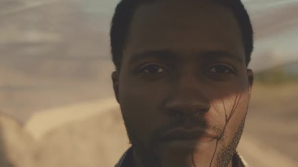 오렌지 일몰에 사막에 카메라를 아프리카계 미국인 남자의 슬로우 클로즈업 초상화 — 비디오