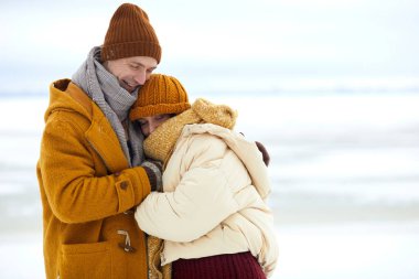 Waist up portrait of loving young couple embracing in minimal winter landscape, copy space clipart