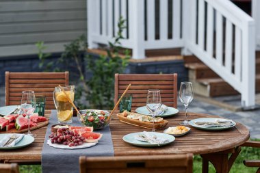 Yaz partisi için dışarıda taze meyve ve böğürtlenlerle hazırlanan şenlikli yemek masasının arkaplan görüntüsü.