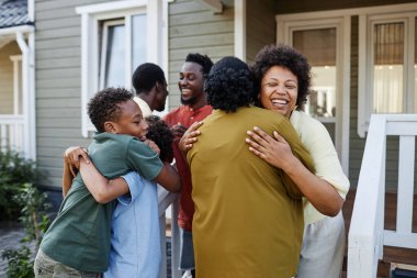 Büyük Afro-Amerikan ailesi parti için açık havada misafirleri kucaklıyor.