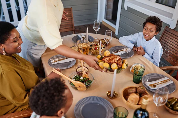 Happy African American family gathering at dinner table outdoors in cozy setting