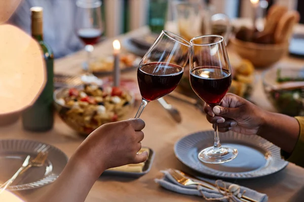 Close up of family clinking wine glasses at dinner table outdoors, cozy evening setting