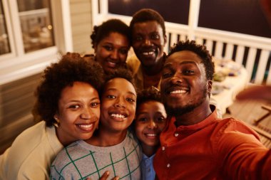 Mutlu Afro-Amerikan aile portresi akşamları terasta selfie çekiyor.