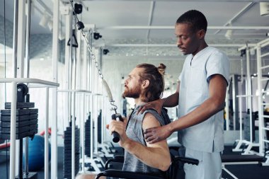 Rehabilitasyon sırasında egzersiz malzemeleriyle özürlü bir Afrikalı doktor tarafından eğitilmiş.