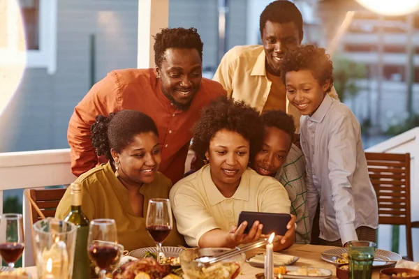 Portrait of African American family taking selfie photo at dinner in evening