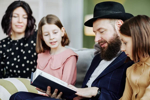 Evde çocuklara kitap okuyan Ortodoks Yahudi 'nin yan görünüm portresi