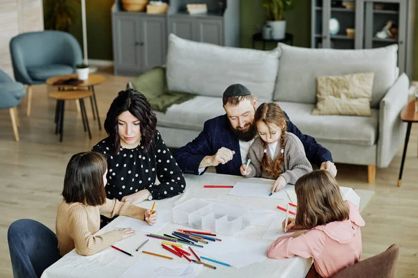 High angle portrait of jewish family drawing together while sitting at table at home with three children