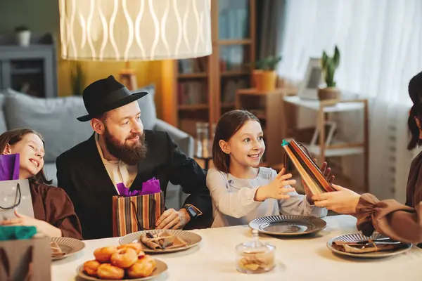 Cozy portrait of modern jewish family sharing gifts at dinner table while celebrating religious holidays