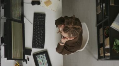 Kafkasyalı kadın programcının gözlük takıp kollarını açarken modern ofisteki masaüstü bilgisayarında kod yazışının üst görüntüsü.