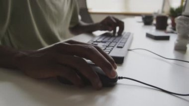 Ofisteki çalışma masasında kablolu bilgisayar faresi kullanan siyah erkek yazılım mühendisinin tanınamaz hale gelen eli.