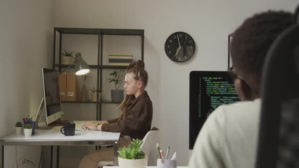 若い疲れた白人女性プログラマーは 彼女の腕を伸ばし 背中を伸ばし 同僚とオープンスペースオフィスで働いている間 机で頭の回転を行います — ストック動画
