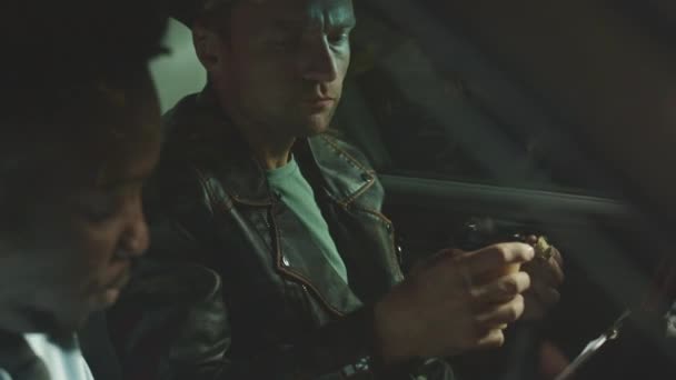 任務中に犯罪者を捕まえようとしながら 夜遅くに車でチャットしてコーヒーを飲む2人の多種多様な犯罪捜査官を待つ — ストック動画