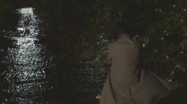 Nehir kıyısına giderken elinde silah tutan, uzun deve siperli cesur Afro-Amerikan erkek dedektifi