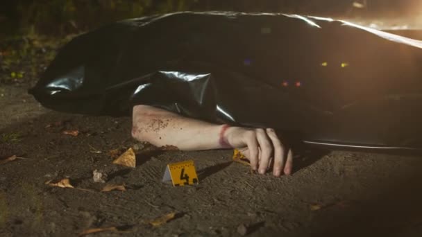 夜间无人在黑色塑料袋和黄色法医标志下拍摄尸体 尸体上有挣扎的痕迹 第四号标志在寒冷的地面上 — 图库视频影像