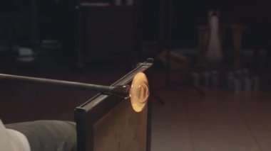 Atölyede paslanmaz çelik cımbızla esnek cam şekillendiren tanınmaz hale getirilmiş cam üfleyici yakın plan.