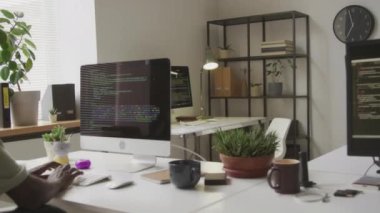 Rastalı genç beyaz kadın çalışma masasında koltuğunu alıyor ve çalışma gününde minimalist açık uzay ofisinde program kodlamaya başlıyor.