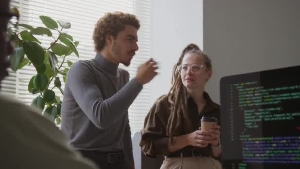 白人男性ソフトウェアエンジニアとクリエイティブなアイデアを共有するBiracial男性ソフトウェアエンジニアのミディアムショット オフィスでコーヒー休憩中にチャット 若い黒人男性が前景でコーディング — ストック動画