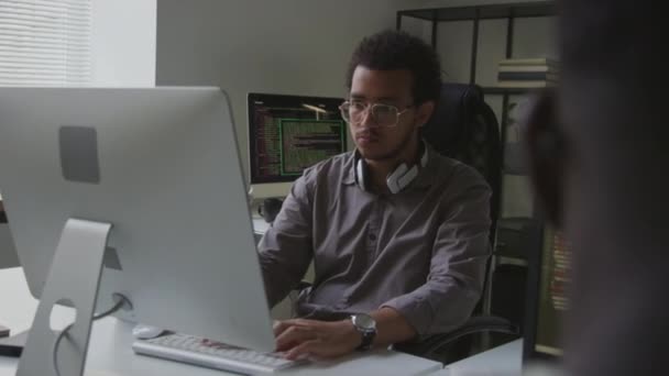 オープンスペースオフィスでコンピュータに取り組む若いBiracial男を待って 新しいソフトウェアをコーディングして開発する — ストック動画