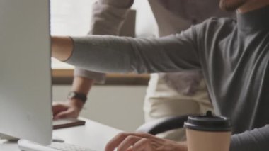 Modern açık uzay ofisinde çalışırken bilgisayar ekranına bakan ve programı veya uygulamayı tartışan iki çift ırklı erkek programcı