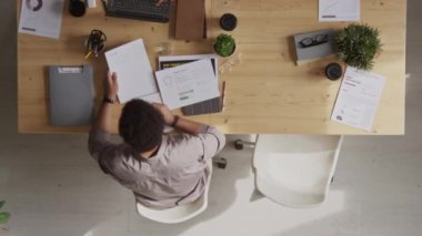 Kafkasyalı genç bir kadının laptopunu ahşap ofis masasına koyması ve erkek arkadaşının yanında evrak işleriyle uğraşırken işe oturması.