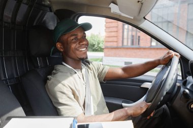 Güneş ışığında teslimat minibüsü süren genç siyahi adamın yan görünümü, kopyalama alanı