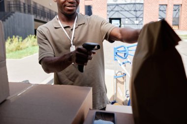 Minibüs boşaltılırken teslimatçının paketlerdeki kodları tararken kesilen görüntüsü