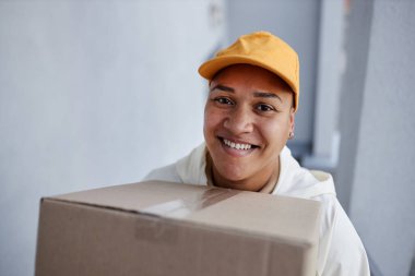 Gülümseyen teslimat işçisinin portresi. Merdivenlerden eve paketle çıkıyor, boşluğu kopyalıyor.