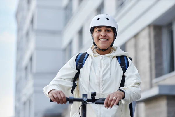 都市の電動スクーターに乗っている間ヘルメットを身に着けている笑顔の食糧配達労働者の肖像画を コピースペース — ストック写真