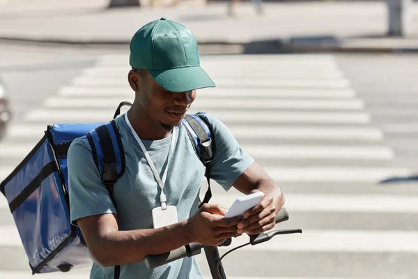 年轻黑人男子在城市送餐时使用智能手机的肖像 复制空间 — 图库照片