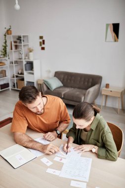 Ev dersinde yeni konuyu öğrenciye açıklayan genç öğretmenin bakış açısının üzerinde ödev veya verilerle belgeye işaret ederken