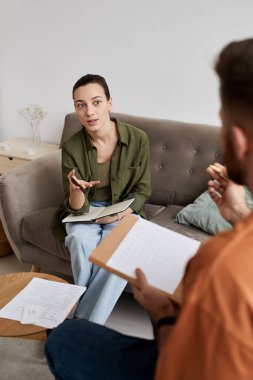 Öz güvenen özel öğretmen ev dersinde önünde otururken öğrenciyle yeni konuları tartışıyor.