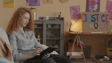 Uzun kıvırcık saçlı, beyaz feminist bir kadının protesto etmeden önce evde cinsiyet eşitliği hakkında motivasyon konuşması yazarken orta boy fotoğrafı.
