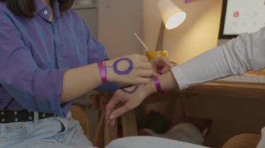 Saldırıya geçmeden, cinsiyet eşitliği ve kadın hakları için savaşmadan önce bileklerine mor kurdele bağlayan feminist hareketi destekleyen tanınmamış iki kadının kesikli çekimi.