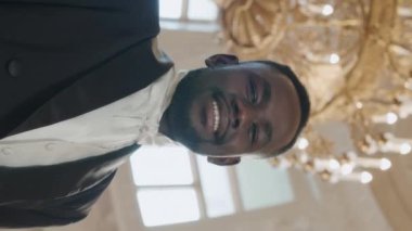 Düşük açılı dikey bel yukarı Viktorya tarzı balo salonunda pahalı avizenin altında kameraya gülümseyen siyah erkek Dük 'ün yavaş yavaş portresi.