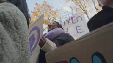 Elinde pankartlar ve posterler olan, feminist meselelerle ilgili grevde olan, sokakta durup motivasyon sloganları atan çok ırklı kadınların düşük açılı görüntüleri.