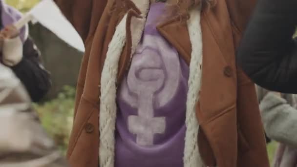 フェミニストのシンボルで紫色のTシャツを着た若い白人女性が 他の女性活動家との屋外での抗議で女性の権利のために戦っている間 叫び声を上げた — ストック動画