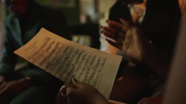 Afrika kökenli Amerikalı kadın caz vokalisti ellerinde notalarla caz kulübündeki konser provası sırasında grup üyeleriyle şarkı sözlerini ve melodileri tartışırken.